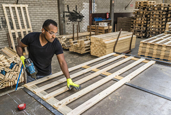 Medewerkers pallet in elkaar zetten